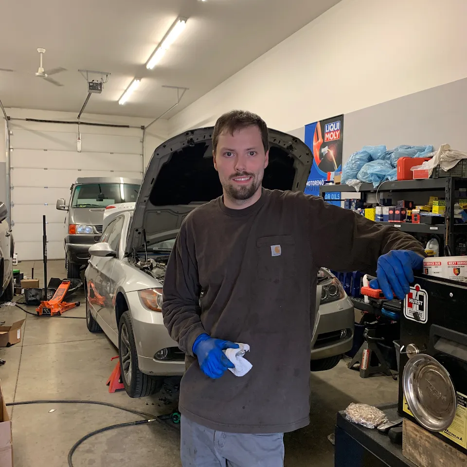 In the shop: a technician, a car on the lift behind him